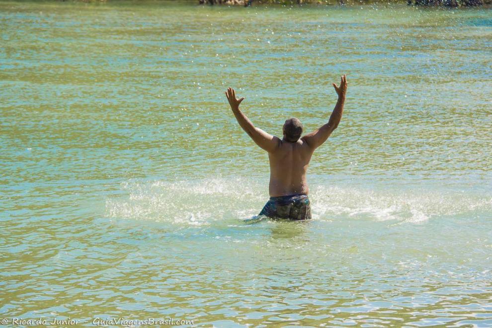 Imagem de homem no mar com braços levantados curtindo a Praia de Jeribucaçu.
